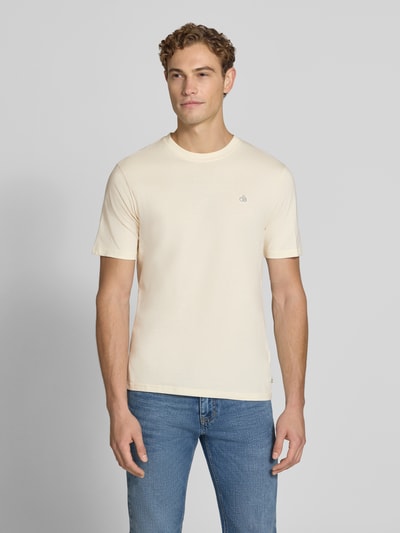 Männermodel trägt Regular Fit T-Shirt aus reiner Baumwolle von Scotch & Soda in Beige mit Logo-Stitching, Rundhalsausschnitt, Ganzkörperansicht von vorne.