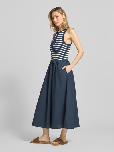 Modelka kobieca nosi A-Linie Freizeitkleid aus reiner Baumwolle od Tommy Hilfiger, granatowe, prążkowane, szerokie ramiączka, bawełniany mix, długość maxi, rozkloszowany fason, kieszenie boczne, widok całej sylwetki z przodu.