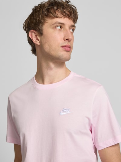 Mannenmodel draagt T-shirt met labelstitching van Nike in lichtroze, puur katoen, regular fit, ronde hals, ruglengte maat M 73 cm. Nahaufnahme bovenlichaam.