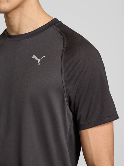 Männermodel trägt T-Shirt mit Logo und Rundhalsausschnitt van PUMA PERFORMANCE, regular fit, donkergrijs met logo, detailopname bovenlichaam.