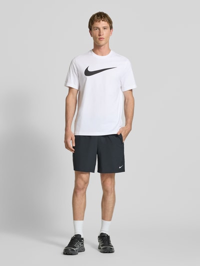 Männermodel trägt Herren T-Shirt mit Logo-Print Modell 'Swoosh' von Nike, Reine Baumwolle, Gerader-Schnitt, Rundhalsausschnitt, Rückenlänge 73 cm, Ganzkörperansicht von vorne.