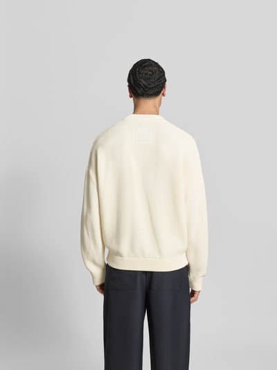 Männermodel trägt Strickjacke mit floralem Stitching von MAISON KITSUNÉ aus cremefarbenem Baumwoll-Mix, Regular-Fit, Rückenansicht. Rückenlänge 70 cm, Schulterbreite 45 cm, Ärmellänge 70 cm, elastische Abschlüsse, durchgehende Knopfleiste.