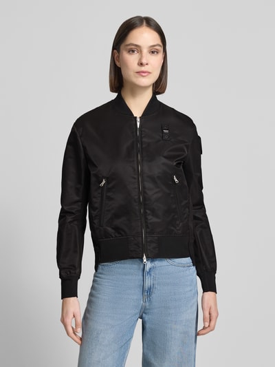 Frauenmodel trägt Bomberjacke mit Reißverschlusstaschen Modell 'LAURIE' von Blauer Usa in Schwarz, gerippte Abschlüsse, Ganzkörperansicht von vorne. Rückenlänge bei Größe S: 57 cm, Schulterbreite: 44 cm, Brustweite: 43 cm, Ärmellänge: 62 cm.