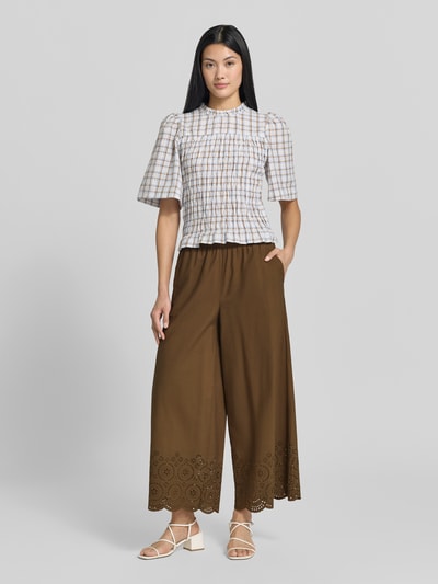 Modelka nosi Wide Leg Culotte aus reiner Baumwolle od s.Oliver RED LABEL w kolorze brązowym, szerokie nogawki, ażurowe wykończenie, pełen widok z przodu.