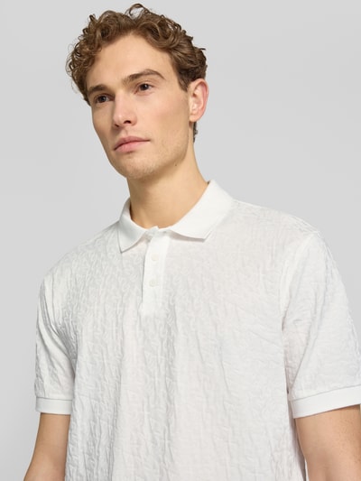 Männermodel trägt Regular Fit Poloshirt mit Strukturmuster von ARMANI EXCHANGE aus reiner Baumwolle, Knopfleiste, Nahaufnahme Oberkörper.