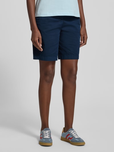 Vrouwenmodel draagt Regular Fit Chino-Shorts uit mix van katoen en lyocell van Tommy Hilfiger, look: effen, gestikt logo, steekzakken, knoop- en ritssluiting, achterzakken, regular fit pasvorm. Detailopname, benen.