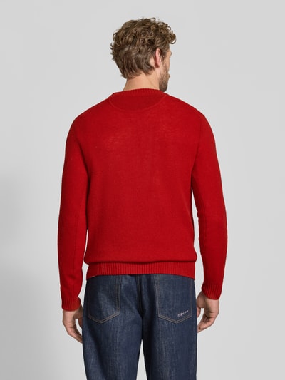 Männermodel trägt Slim Fit Strickpullover aus reiner Wolle mit Label-Stitching von MCNEAL in Rot, gerippte Abschlüsse, Ganzkörperansicht Rückansicht. Rückenlänge 66 cm, Ärmellänge 69 cm.