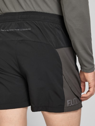 Männermodel trägt schwarze Herren Shorts mit elastischem Bund und Reißverschlusstaschen Modell 'HALO DIVISION' von HALO, Detailaufnahme Rückansicht, Regular-Fit, Bundweite 40 cm, Innenbeinlänge 10 cm, glattes Material mit Mesh-Struktur.