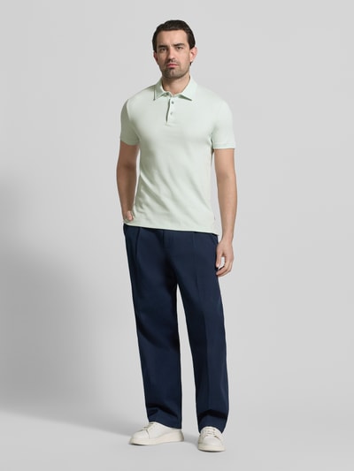 Männermodel trägt Slim Fit Poloshirt aus reiner Baumwolle Modell 'PALOSH 30' von BOSS in Unifarbe mit Polokragen, Ganzkörperansicht von vorne.