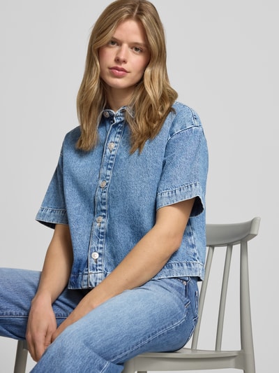 Frauenmodel trägt Loose Fit Jeansbluse aus reiner Baumwolle Modell 'SKY' von Pieces in Denim-Optik mit Knopfleiste, Nahaufnahme Oberkörper.