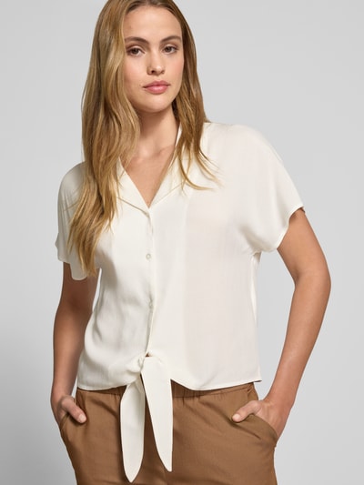 Frauenmodel trägt Regular Fit Bluse aus Viskose mit Knotendetail Modell 'RADIA' von Soyaconcept, Reine Viskose, Reverskragen, Knopfleiste, Rückenlänge bei Größe S 55 cm, Ärmellänge 10 cm, cremefarbener Stoff mit glatter Textur, Nahaufnahme Oberkörper.