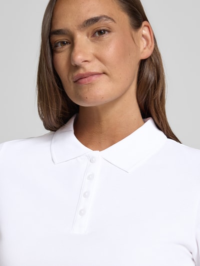 Modelka kobieca nosi Regular Fit Poloshirt aus Baumwoll-Mix od s.Oliver RED LABEL, efekt: jednolity kolor, krój regular fit, kołnierzyk polo, rękaw: krótki rękaw, wykończenie materiału: pika, mieszanka bawełny, zbliżenie na górną część ciała