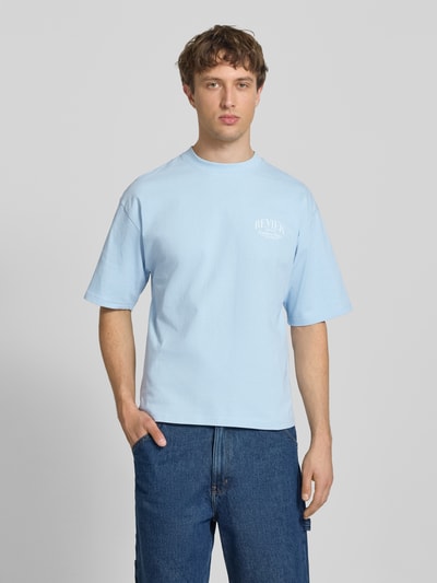 Männermodel trägt T-Shirt mit Label-Detail von REVIEW in Hellblau, Reine Baumwolle, Lockerer-Schnitt, Rundhalsausschnitt, 1/2-Arm, Ganzkörperansicht von vorne. Rückenlänge bei Größe M: 68 cm.