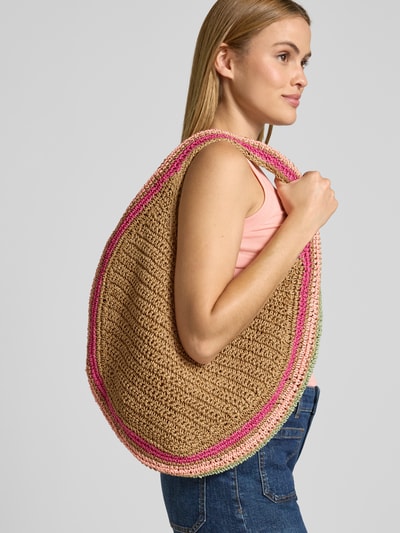 Frauenmodel trägt Handtasche mit Label-Detail Modell 'Saunteer' von Barts, Naturtöne mit rosa Akzenten, Schulterriemen, Ganzkörperansicht von vorne, Innenfach mit Reißverschluss, Maße: Breite 45 cm, Länge 32 cm, Tiefe 12 cm, Riemenlänge 36 cm.