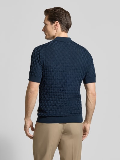 Męski model nosi Slim Fit Poloshirt aus reiner Baumwolle Modell 'Heritage' von Matinique, granatowy kolor, tekstura koszulki z wyraźnym wzorem, prążkowane wykończenia, krój slim fit, czysta bawełna, całkowity widok sylwetki od tyłu.