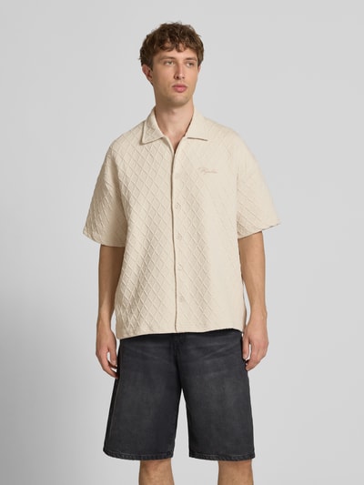 Männermodel trägt Modern Fit Freizeithemd mit Logo-Stitching Modell 'Jovren' von Pegador, beige Farbe, Strukturmuster, Ganzkörperansicht von vorne.