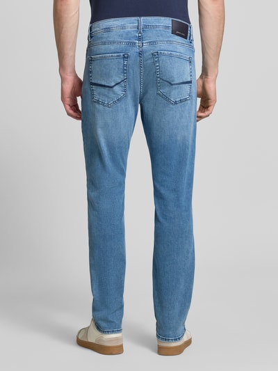 Męski model nosi Tapered Fit Jeans im Used-Look Modell 'Lyon' od Pierre Cardin, bawełniany miks z wiskozą, jasnoniebieski, tylna pełna sylwetka, Szerokość w rozmiarze 32/32: 42 cm, długość nogawki wewnętrznej: 79 cm.