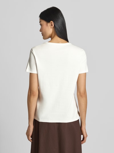 Frauenmodel trägt T-Shirt mit Motiv-Print und Rundhalsausschnitt von Marc Cain aus reiner Baumwolle, Slim Fit, Rückenlänge 51 cm, Ganzkörperansicht Rückansicht.