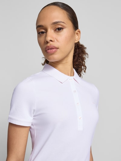 Vrouwenmodel draagt Knielanges Polokleid met Label-Stitching van Gant in lichtroze, mix van katoen en elastaan, recht model, knielengte, knoopsluiting, labelstitching, ruglengte maat S 95 cm, borstwijdte maat S 41 cm, mouwlengte maat S 20 cm, close-up bovenlichaam.