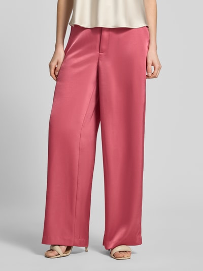 Frauenmodel trägt Satinhose mit angedeuteten Gesäßleistentaschen Modell 'Emmett' von Neo Noir in Satin, Wide-Fit, Nahaufnahme Unterkörper. Bundweite bei Größe 36: 39 cm, Innenbeinlänge bei Größe 36: 86 cm, mit Haken-Reißverschluss und französischen Eingrifftaschen.