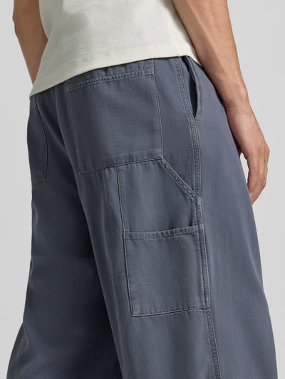 Männermodel trägt Wide Fit Jeans mit teilelastischem Bund Modell 'Lycaz' von American Vintage, reine katoen, grijze kleur, grote opgestikte achterzakken, knoop- en ritssluiting, context: heren jeans, binnenbeenlengte maat M 71 cm, taillewijdte 39 cm, detailopname achterkant.