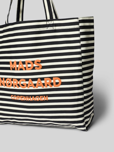 Produktfoto, Shopper aus Baumwolle mit Logo Modell 'Boutiqno Athene' von MADS NØRGAARD, schwarz-weiß gestreift, orangefarbener Schriftzug, grob gewebte Textur, breite Tragehenkel, strukturierte, rechteckige Form, offenes Hauptfach, Maße 37x35x11 cm, Schulterriemen 61 cm.