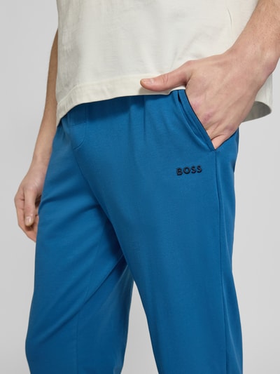 Männermodel trägt Regular Fit Sweatpants aus Baumwoll-Mix von BOSS in Blau mit Label Stitching, seitlichen Taschen, Nahaufnahme Oberkörper.