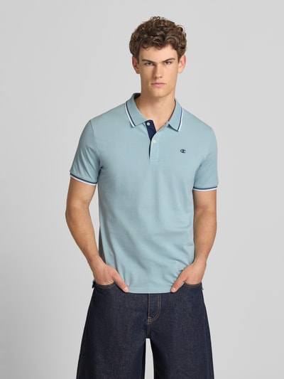 Mężczyznamodel nosi Slim Fit Poloshirt mit Label-Stitching von CHAMPION z bawełny, krój slim fit, listwa guzikowa, długość tyłu 73 cm w rozmiarze M; widok na cały przód.