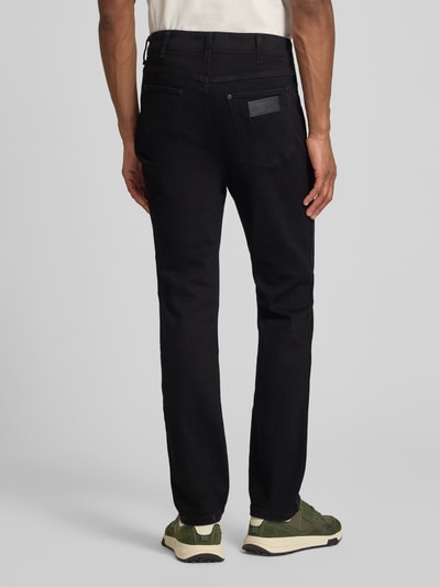 Männermodel trägt Straight Fit Jeans im 5-Pocket-Design Modell 'Greensboro' von Wrangler, schwarze Farbe, Baumwoll-Mix mit Stretch-Anteil, Gerader-Schnitt, Ganzkörperansicht Rückansicht.
