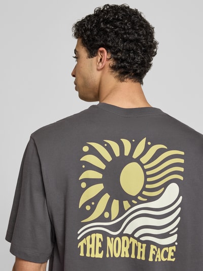 Männermodel trägt Oversized T-Shirt mit Logo-Print von The North Face in Dunkelgrau, reine Baumwolle, Rückansicht, Nahaufnahme Oberkörper.