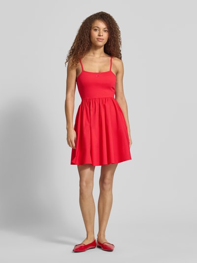 Frauenmodel trägt Tailliertes Freizeitkleid aus reiner Baumwolle von Tommy Jeans, efekt: jednolity kolor, krój: taliowany, długość: mini, dekolt w łódkę, wyhaftowane logo, cienkie ramiączka, prosty dół, wpuszczane kieszenie, materiał: bawełna, Ganzkörperansicht von vorne.