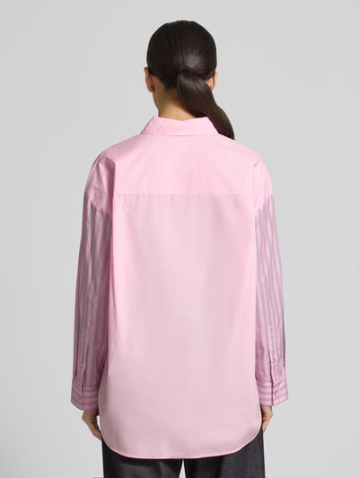 Männermodel trägt Relaxed Fit Hemdbluse aus reiner Baumwolle Modell 'JOLIVIA' von Essentiel Antwerp, różowy kolor, pionowe paski, logo-stitching, długi rękaw z mankietem, bawełna, krój relaxed fit, unikalny wzór allover, plecy z karczkiem, zapięcie na pojedyncze guziki, widok całej sylwetki z tyłu.
