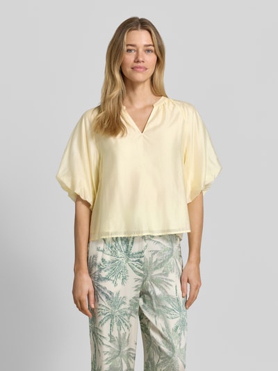 Frauenmodel trägt Loose Fit Blusenshirt aus Lyocell-Mix von s.Oliver BLACK LABEL, Optik: Unifarben, V-Ausschnitt, Raffung, Puffärmel, Raglanärmel, elastischer Ärmelabschluss, glatte Textur, sanfte Pastellfarbe, Ganzkörperansicht von vorne.