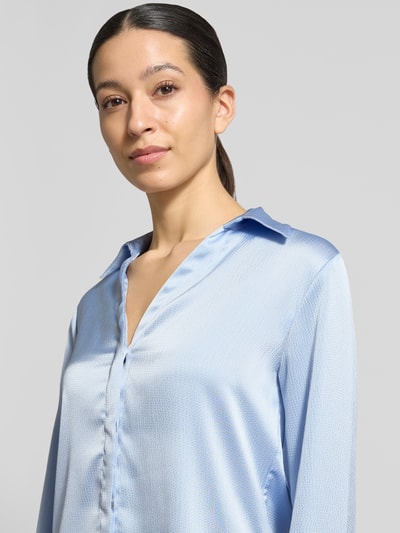 Frauenmodel trägt Regular Fit Bluse mit V-Ausschnitt von Calvin Klein Womenswear in Hellblau, fein strukturierte Oberfläche, Nahaufnahme Oberkörper.