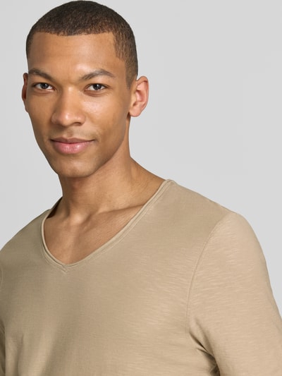 Mężczyznę model nosi Regular Fit T-Shirt mit V-Ausschnitt von MCNEAL, bawełna, krój regular fit, dekolt w serek, zrolowany brzeg, długość tyłu 70 cm w rozmiarze M, jasnobeżowy, gładka tekstura, zbliżenie na górną część ciała