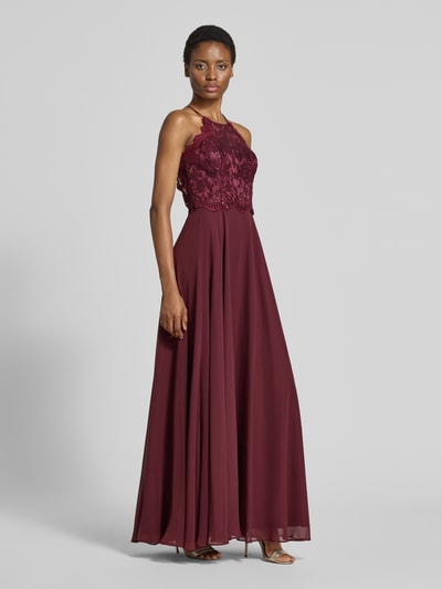 Modelka nosi sukienkę wieczorową 'Abendkleid mit floralem Spitzenbesatz' od Vera Mont z szyfonu, góra z cekinowym obszyciem, okrągły dekolt, krój bez rękawów, długość do ziemi, wszyty zamek błyskawiczny, wycięcie na plecach, rozmiar 36: długość tyłu 155 cm, szerokość w rozmiarze 36: 34 cm, pełny widok z przodu.