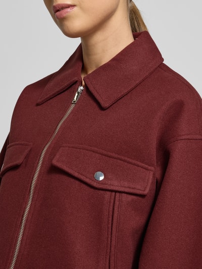 Kobiece model prezentuje Regular Fit Hemdjacke mit Reißverschluss Modell 'FORTUNEFREJ' od Vero Moda, jednolity filc, kieszenie z patką, kolor ciemnoczerwony, zbliżenie na górną część ciała.