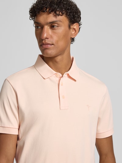 Männermodel trägt Modern Fit Poloshirt mit Logo-Stitching Modell 'Primo' von JOOP! Collection in zartem Rosa, Nahaufnahme Oberkörper. Baumwolle, Polokragen, kurze Knopfleiste, dezente Logo-Stickerei und Label-Detail sind erkennbar.
