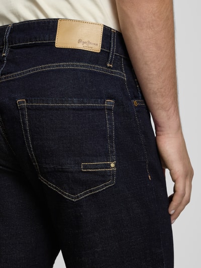 Männermodel trägt Regular Fit Jeans aus Baumwoll-Mix Modell 'Cash' von Pepe Jeans in dunklem Denim mit Label Patch, Nahaufnahme Rückansicht.