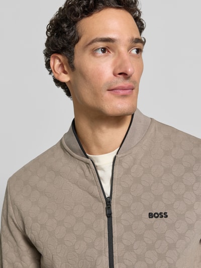 Männermodel trägt Regular Fit Sweatjacke aus Baumwoll-Mix Modell 'SW_Revival Skarley' von BOSS, beige Farbe, strukturierte Oberfläche, Nahaufnahme Oberkörper, Herren Sweatjacke von BOSS.