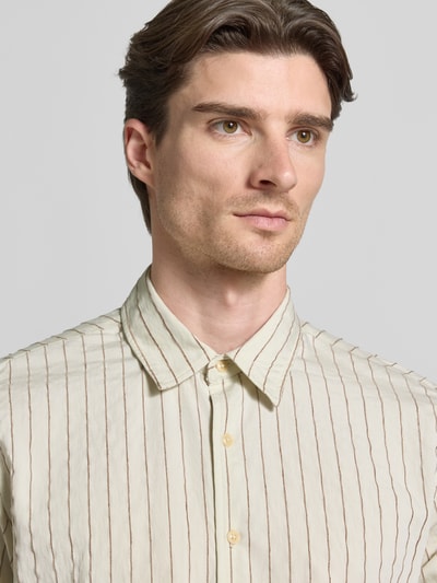 Männermodel trägt Regular Fit Freizeithemd mit Viskose-Anteil Modell 'REDFORD' von Guess in Beige mit braunen Streifen, Nahaufnahme Oberkörper.