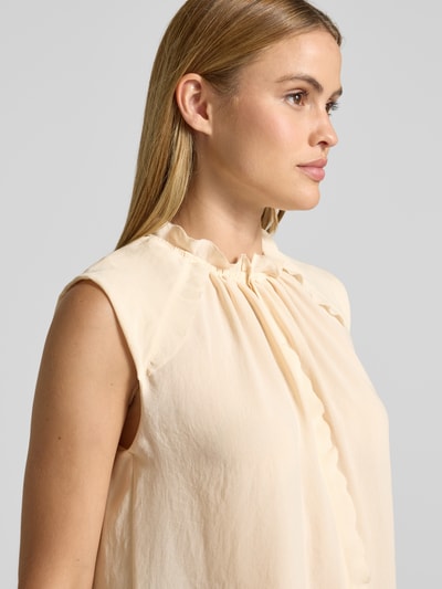 Frauenmodel trägt Blusenshirt mit Rüschen und Kappärmeln von Marc Cain in Creme, glatte Textur, Rundhalsausschnitt, Nahaufnahme Oberkörper.