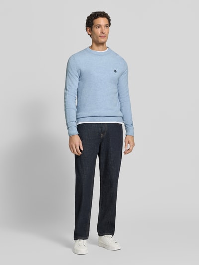 Männermodel trägt Slim Fit Strickpullover aus reiner Wolle mit Label-Stitching von MCNEAL, hellblau, gerade Formen, Struktur durch Rippbündchen, Herren Strickpullover, Ganzkörperansicht von vorne.