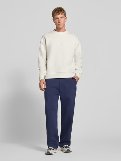 Męski model nosi Regular Fit Sweatshirt mit Baumwoll-Anteil od JACK & JONES, mieszanka bawełny, okrągły dekolt, elastyczne wykończenia, krój regular fit, długi rękaw, długość tyłu w rozmiarze M: 65 cm, długość rękawów w rozmiarze M: 59 cm, jasny kolor, gładka faktura, widok całej sylwetki od przodu.