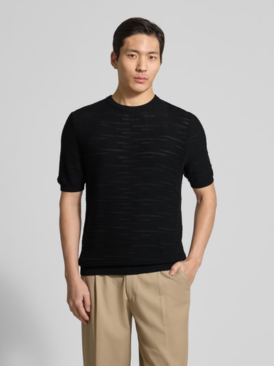 Männermodel trägt Strickshirt aus Baumwolle von Antony Morato in Schwarz mit Gerader-Schnitt, Rundhalsausschnitt, Gerippte-Abschlüsse, Halbarm, Ganzkörperansicht von vorne. Rückenlänge bei Größe M: 70 cm.