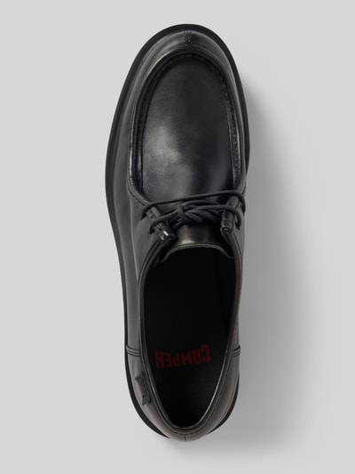 Produktfoto, schwarze Schnürschuhe mit Label-Detail Modell 'Norman' von Camper, abgerundete Spitze, Gummisohle, glatte Oberfläche.