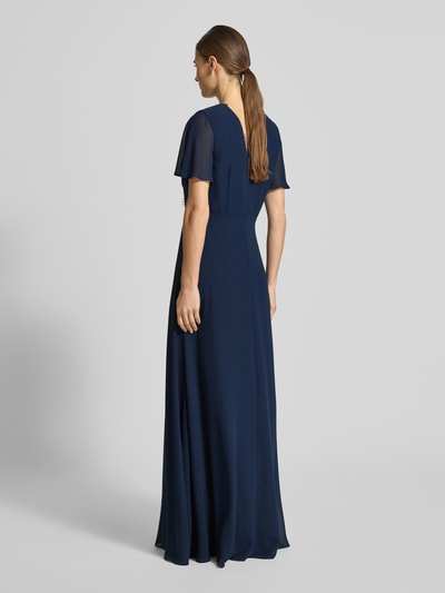 Frauenmodel trägt Damen Abendkleid mit Spitzenbesatz von Christian Berg Cocktail in dunklem Blau, fließender Stoff, taillierte Passform, kurzärmelig, semitransparente Optik, Rückenlänge 139 cm bei Größe 36, Ganzkörperansicht Rückansicht.