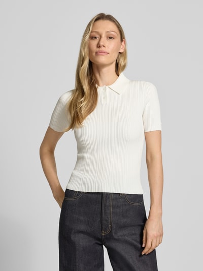 Frauenmodel trägt Slim Fit Strickpullover aus Viskose-Mix Modell 'Sareplette' von HUGO, Strickoptik, Streifen-Struktur, Polokragen, V-Ausschnitt, Kurzarm, Materialverarbeitung: Strick, Farbe creme, Ganzkörperansicht von vorne.