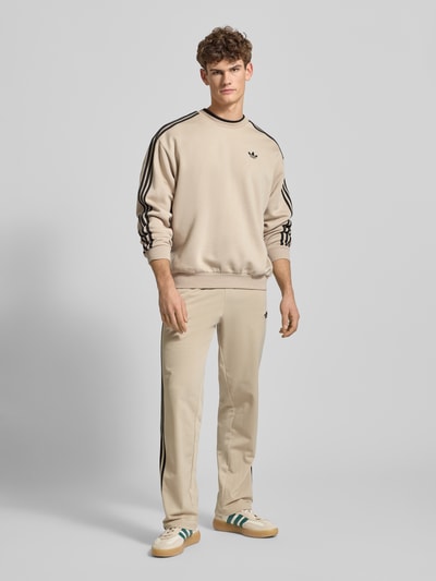 Męski model nosi Bluza mit Label-Stitching od adidas Originals, mieszanka bawełny, krój regular fit, prążkowane wykończenia, okrągły dekolt, długość tyłu 69 cm, długość rękawów 60 cm, jasny kolor, gładka faktura, widok całej sylwetki z przodu.