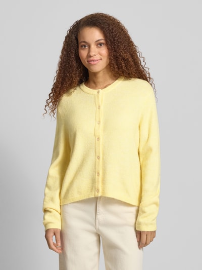 Vrouwenmodel draagt Regular Fit Strickjacke mit einreihiger Knopfleiste Modell 'SIMONI' van Only in effen geel, gebreide textuur, ronde hals, lange mouw met geribde afwerking, vooraanzicht busteshot.